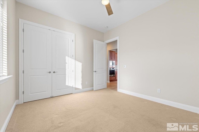 unfurnished bedroom featuring ceiling fan, a closet, and light carpet