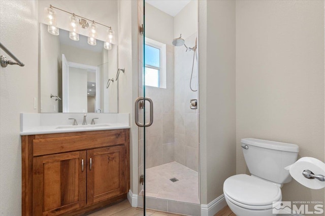 bathroom with tile patterned floors, vanity, toilet, and a shower with door