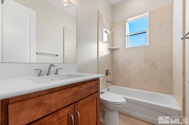 full bathroom with vanity, hardwood / wood-style flooring, toilet, and tiled shower / bath