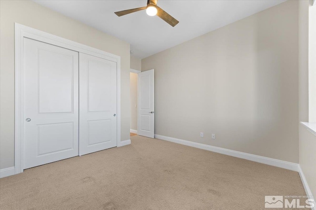 unfurnished bedroom featuring light carpet, a closet, and ceiling fan