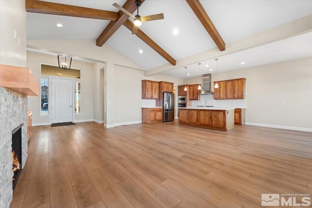 unfurnished living room with a fireplace, lofted ceiling with beams, ceiling fan with notable chandelier, and light wood-type flooring