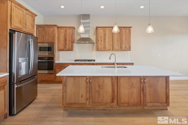 kitchen with a center island with sink, wall chimney exhaust hood, sink, and stainless steel appliances