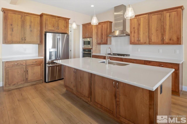 kitchen with wall chimney exhaust hood, light hardwood / wood-style floors, stainless steel appliances, and hanging light fixtures