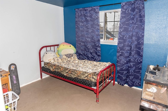 bedroom with concrete floors and baseboards