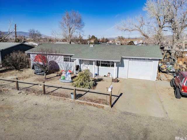 ranch-style house featuring driveway, a fenced front yard, a shingled roof, and an attached garage