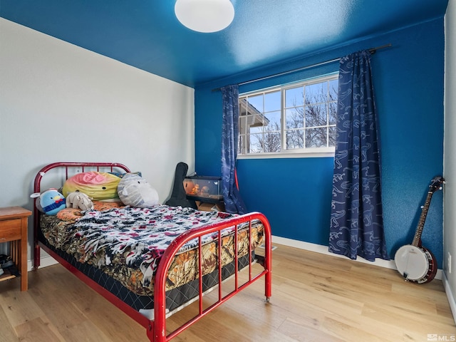 bedroom with wood finished floors and baseboards