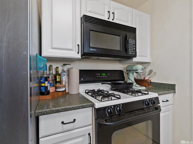 kitchen with black microwave, gas range oven, dark countertops, and white cabinets