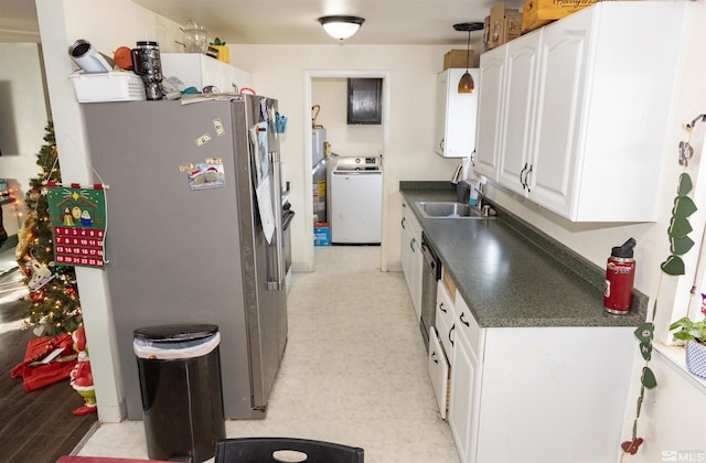 kitchen featuring a sink, freestanding refrigerator, light floors, washer / clothes dryer, and dark countertops