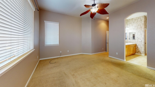 carpeted spare room featuring a wealth of natural light, ceiling fan, and sink