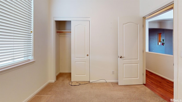 unfurnished bedroom featuring light colored carpet and a closet