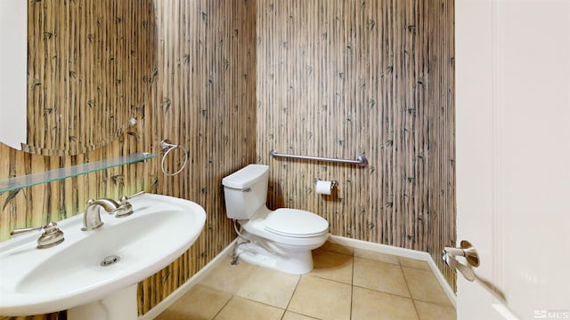 bathroom featuring tile patterned floors, wood walls, toilet, and sink