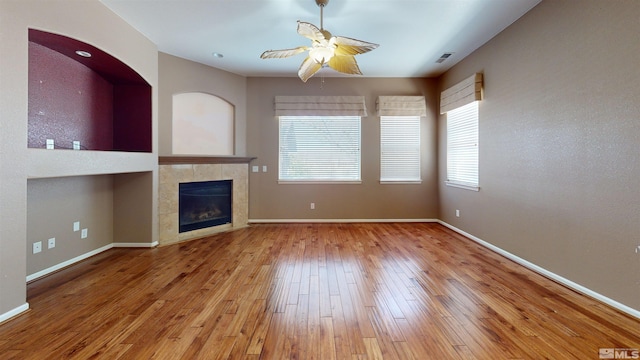 unfurnished living room with a tile fireplace, ceiling fan, and hardwood / wood-style floors