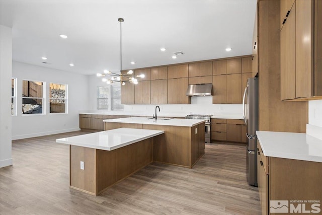 kitchen with a large island, hanging light fixtures, stainless steel appliances, and light hardwood / wood-style floors