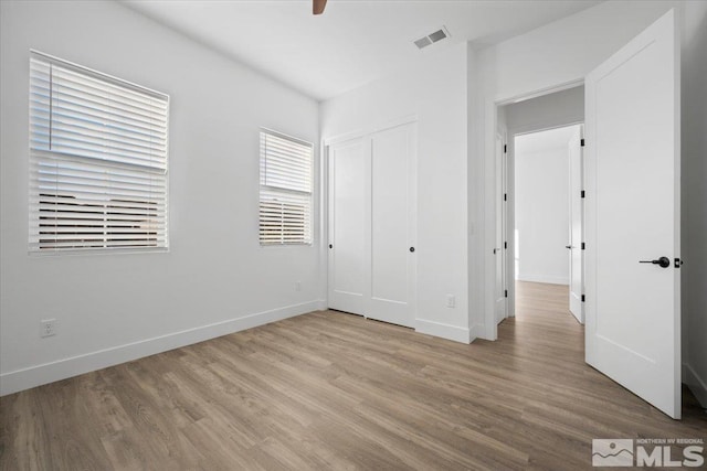 unfurnished bedroom featuring ceiling fan, light hardwood / wood-style flooring, and a closet