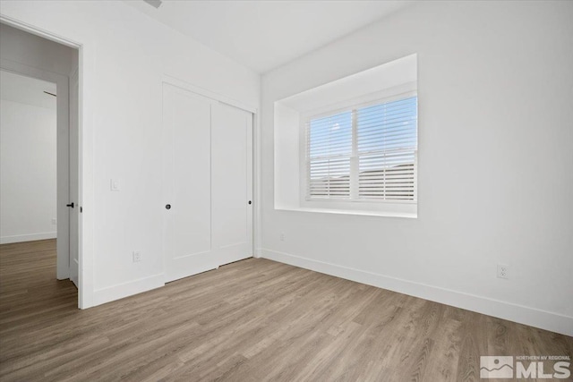 unfurnished bedroom featuring a closet and light hardwood / wood-style flooring