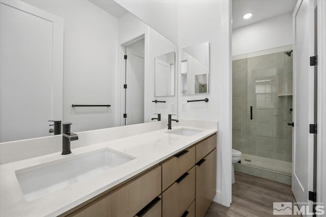 bathroom with toilet, a shower with door, vanity, and hardwood / wood-style flooring