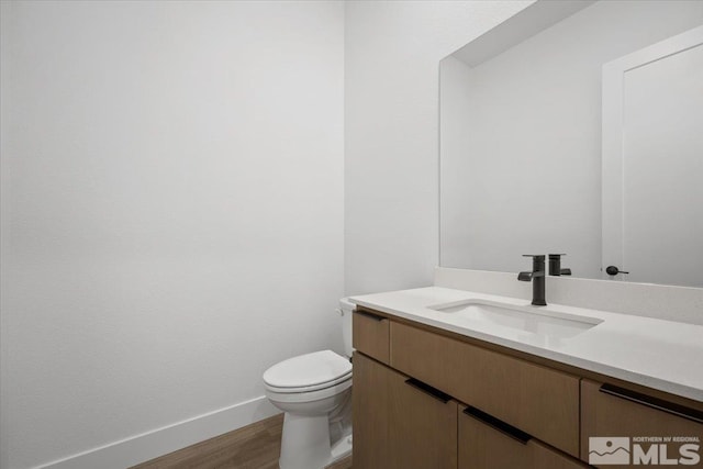 bathroom with hardwood / wood-style floors, vanity, and toilet