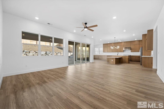 unfurnished living room with ceiling fan, wood-type flooring, and sink