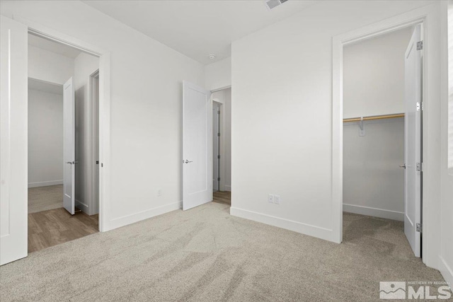 unfurnished bedroom with light carpet, a closet, and a spacious closet