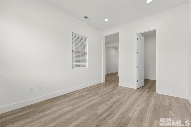 unfurnished bedroom with a spacious closet, light wood-type flooring, and a closet