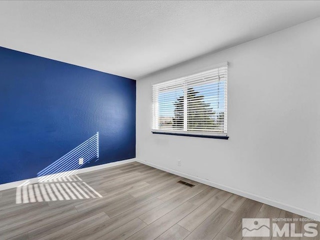 spare room with a textured ceiling and light wood-type flooring