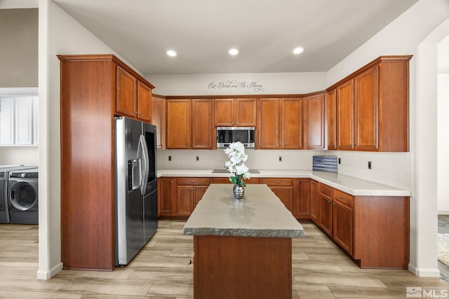 kitchen featuring a kitchen island, light hardwood / wood-style floors, independent washer and dryer, and appliances with stainless steel finishes