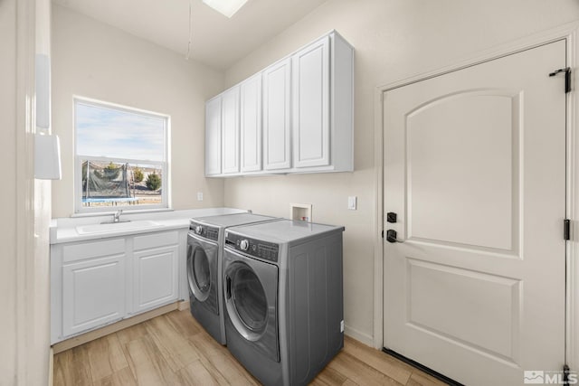 laundry room with independent washer and dryer, sink, cabinets, and light wood-type flooring