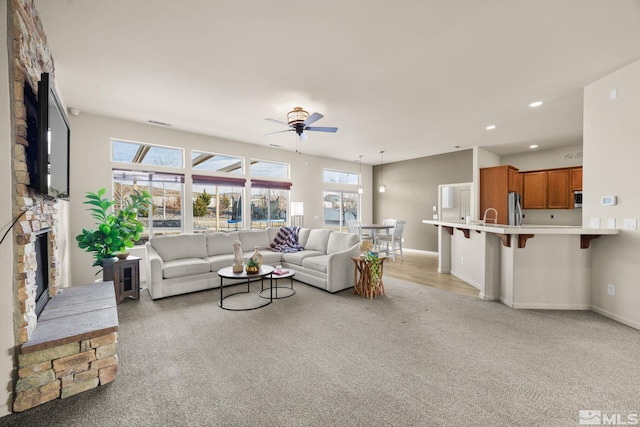 living room with a fireplace, light colored carpet, a wealth of natural light, and ceiling fan