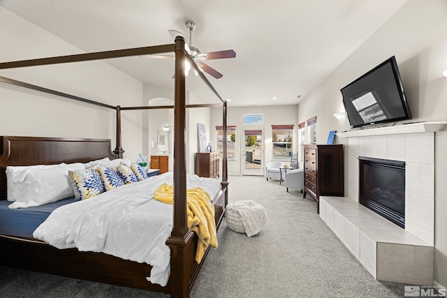 carpeted bedroom featuring ceiling fan and a tiled fireplace