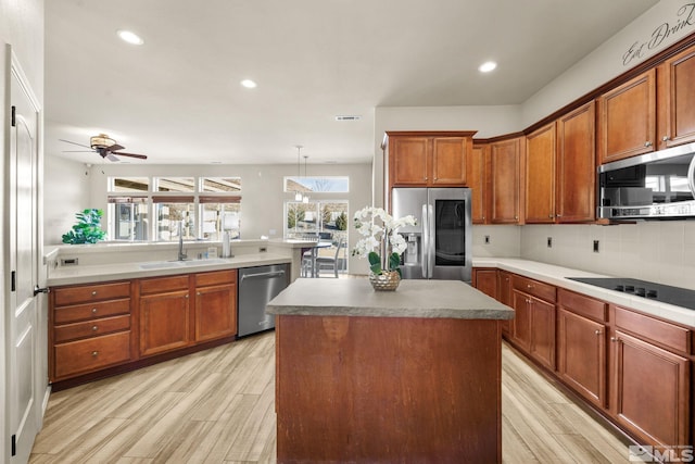 kitchen featuring ceiling fan, a center island, stainless steel appliances, pendant lighting, and light hardwood / wood-style floors