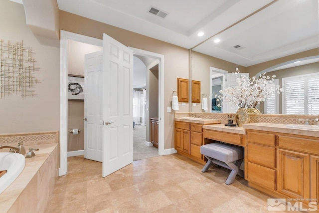 bathroom with vanity and tiled tub