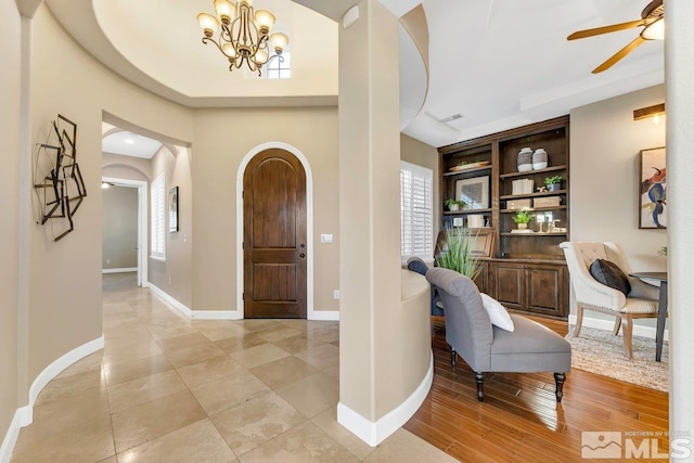 foyer with light hardwood / wood-style floors and ceiling fan with notable chandelier