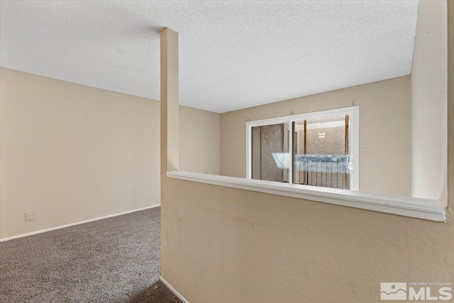 hall featuring a textured ceiling and carpet floors