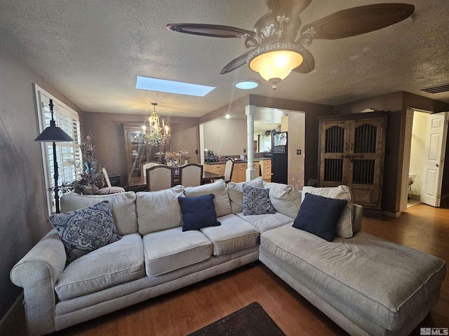 living room featuring a skylight, decorative columns, a textured ceiling, ceiling fan with notable chandelier, and hardwood / wood-style flooring