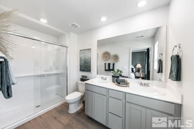 bathroom featuring hardwood / wood-style floors, vanity, toilet, and an enclosed shower