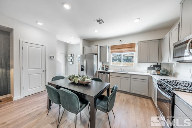 kitchen with stainless steel appliances, light hardwood / wood-style flooring, gray cabinetry, and sink