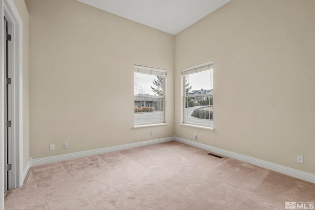 empty room with light colored carpet and lofted ceiling