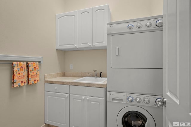 washroom with cabinets, stacked washer / dryer, and sink