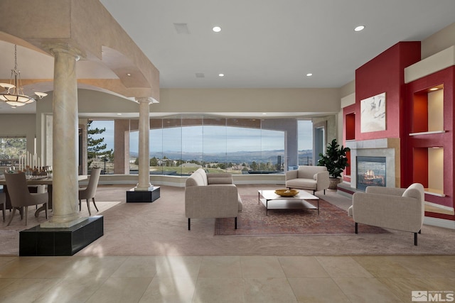 living room with light tile patterned flooring, ornate columns, and a fireplace