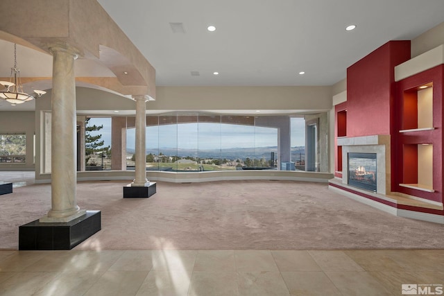 unfurnished living room with light carpet, ornate columns, and a tiled fireplace