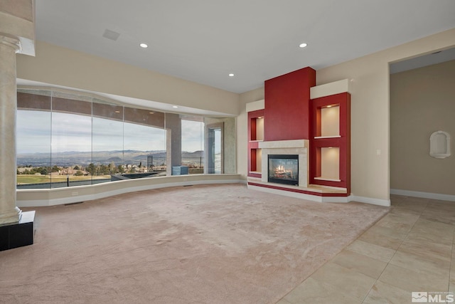 unfurnished living room featuring a mountain view, light colored carpet, and plenty of natural light