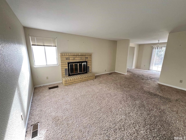 unfurnished living room featuring carpet, an inviting chandelier, and a healthy amount of sunlight