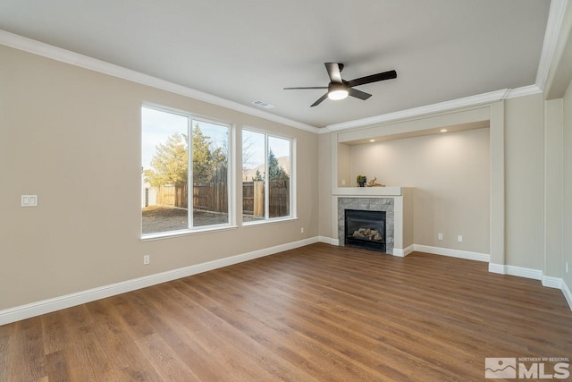 unfurnished living room featuring a tiled fireplace, crown molding, ceiling fan, and wood-type flooring