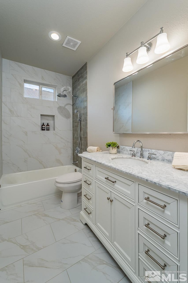 full bathroom with toilet, vanity, and tiled shower / bath