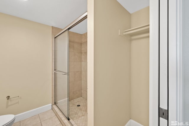 bathroom with tile patterned flooring, a shower with shower door, and toilet