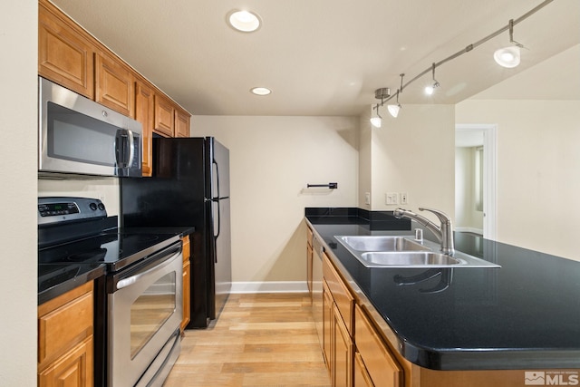 kitchen featuring sink, stainless steel appliances, light hardwood / wood-style flooring, track lighting, and a kitchen island