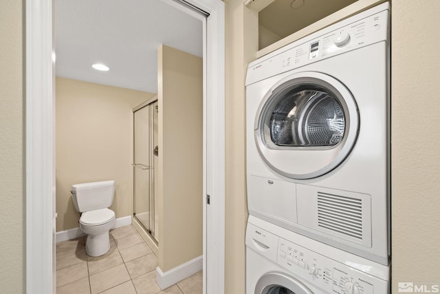 clothes washing area featuring light tile patterned floors and stacked washer and dryer