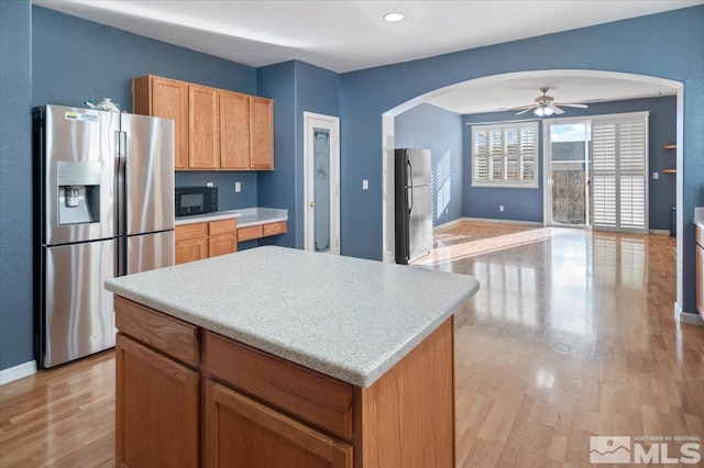 kitchen with stainless steel fridge, ceiling fan, stainless steel fridge with ice dispenser, a center island, and light hardwood / wood-style floors