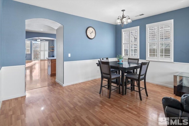 dining area with light hardwood / wood-style flooring and ceiling fan with notable chandelier