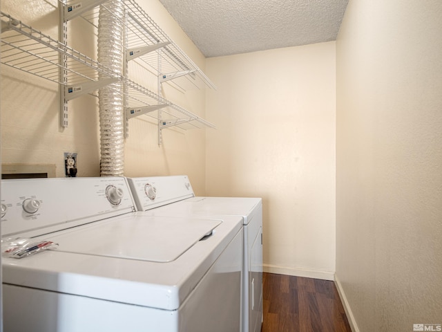 laundry room featuring washing machine and clothes dryer, dark wood-type flooring, and a textured ceiling